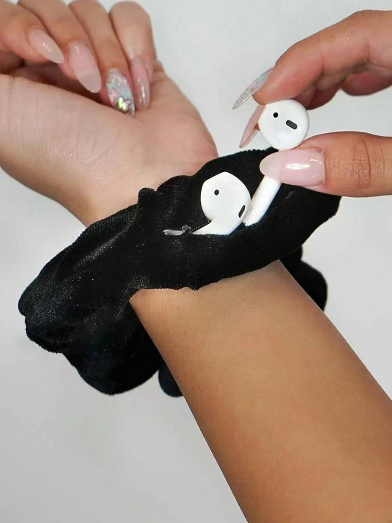 Black scrunchie with white ghost charms held by a person against a neutral background